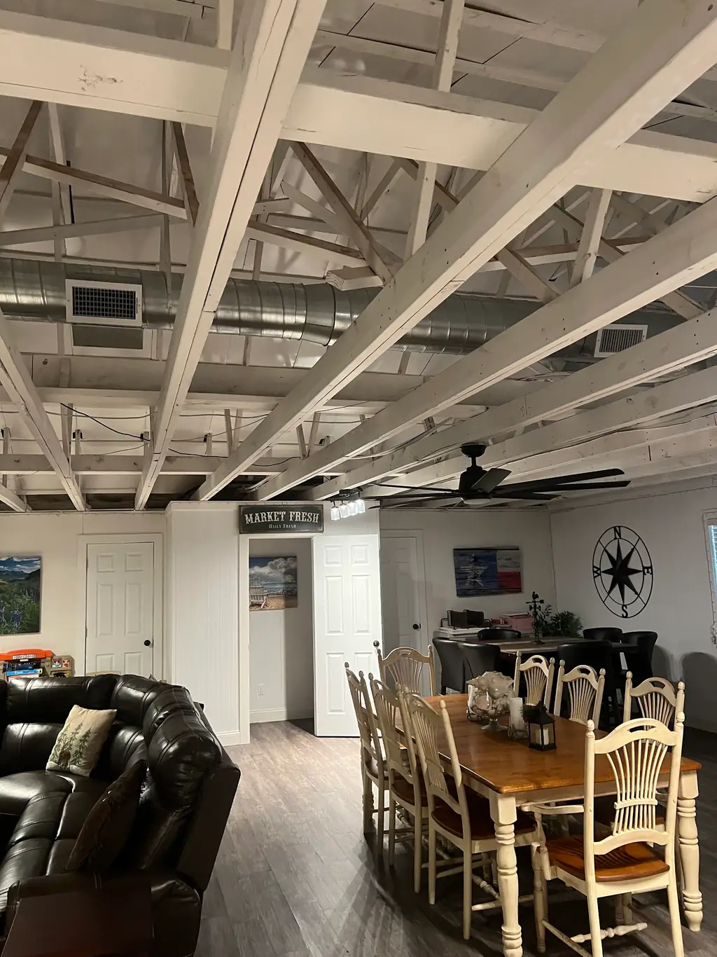 Converted barn game room in Cypress with exposed spiral duct running the length of the white painted trusses