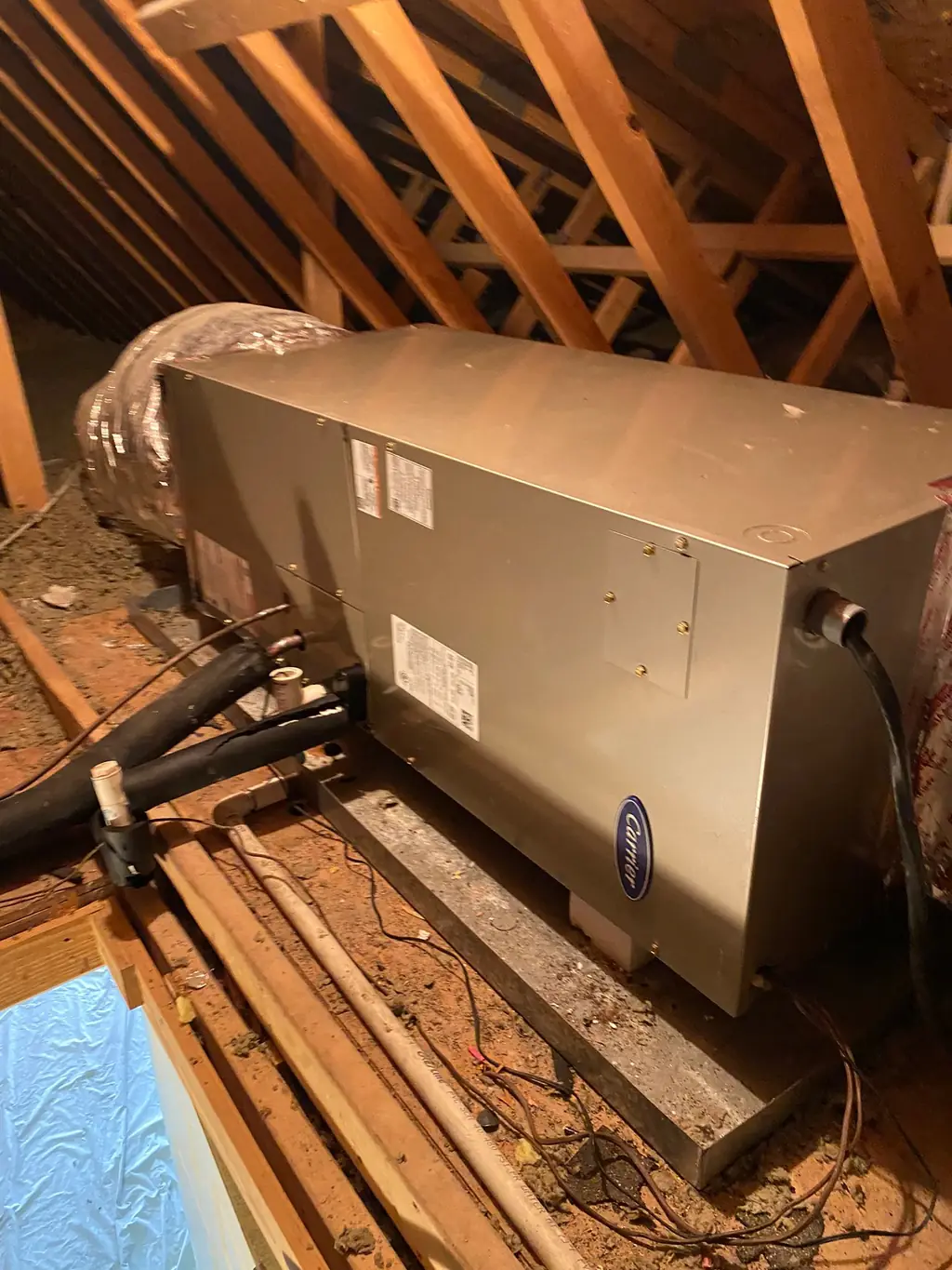 Carrier air handler set on the attic deck with insulated refrigerant lines run to it
